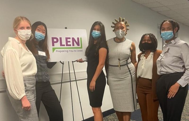 A group of women wearing medical masks stand in front a sign
