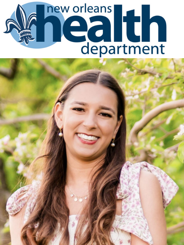 White woman stands in front of trees underneath the logo of New Orleans Health Department