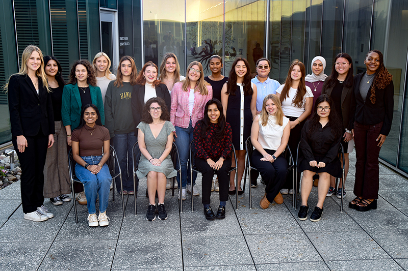 Photo of group of students outside in a courtyard, students in front row are seated, with other standing behind them