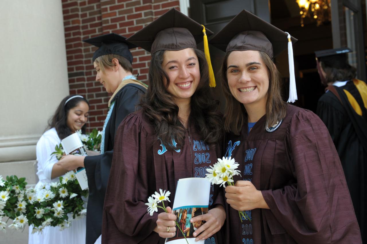 two stand next to each other in graduation regalia 