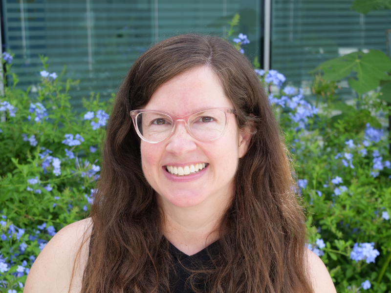 Photo of Elizabeth Hearne in front of blue blooming flowers