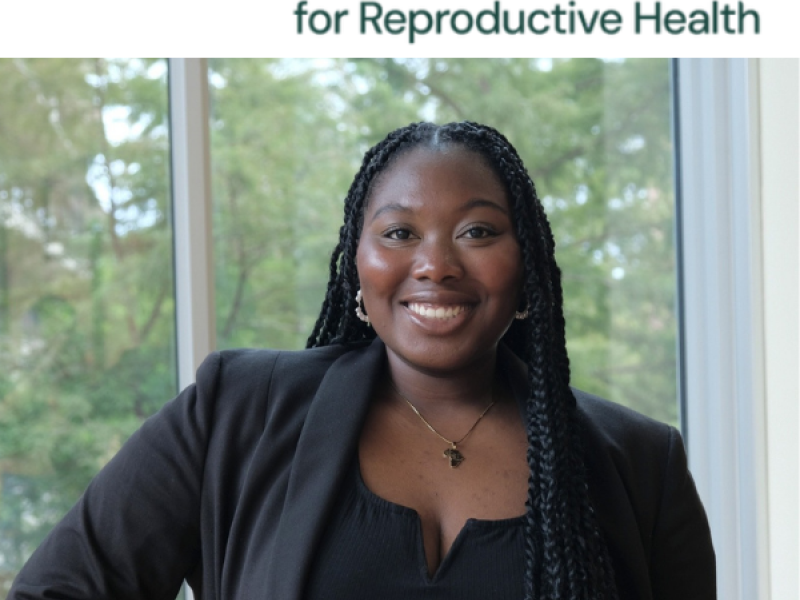 A black woman in a blazer stands in front of trees under the logo for resound research