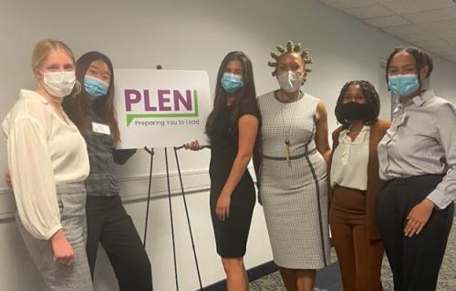 PLEN conference A group of women wearing medical masks stand in front a sign