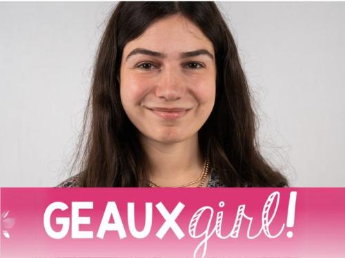 a white girl is in front of a gray background and a pink "geaux girl!" logo is under her face
