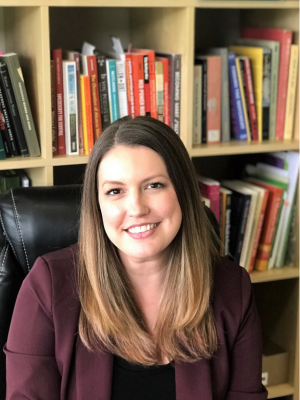 a white woman in front of a bunch of books on a shelf