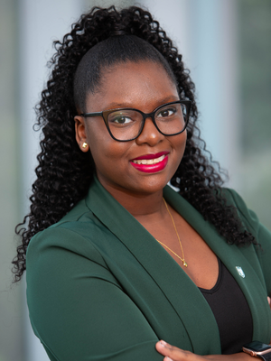Black Woman with a green blazer smiles with her arms crossed