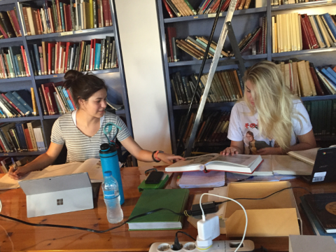 Two students sit at a table in a library comparing notes 