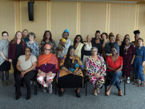 Group photo of Tulane Faculty and community parnters. Some people, some stand, all face the camera in a large meeting room.  