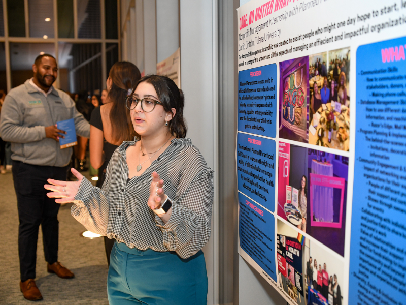 A girl with glasses presents a poster.