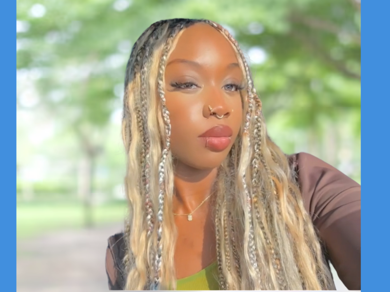 A Black woman with blonde braids poses for a camera